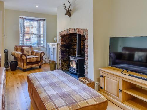 a living room with a fireplace and a bed and a television at Hidden Winds Cottage in Guisborough