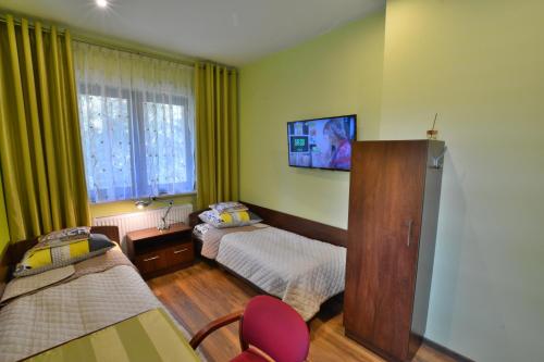 a bedroom with two beds and a tv on the wall at Willa Olympia in Unieście