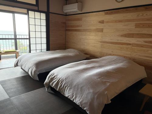 two beds in a room with wooden walls at Yakushima Green Hotel in Yakushima