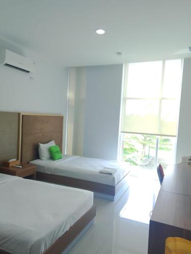 a bedroom with two beds and a large window at Hotel Training Center UIN Mataram in Mataram