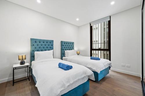 two beds in a room with white and blue at SOP 82 Stylish and Cozy Two-Bedroom Apt in Sydney