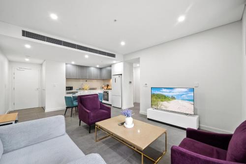 a living room with purple chairs and a tv at SOP 82 Stylish and Cozy Two-Bedroom Apt in Sydney