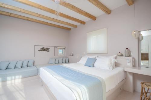a white bedroom with a large bed and a couch at Antony Suites (Adults Only) in Naxos Chora