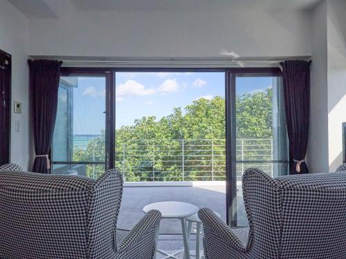 a room with a large window with chairs and a table at CASA DUMAI OceanVilla NAKIJIN in Nakijin