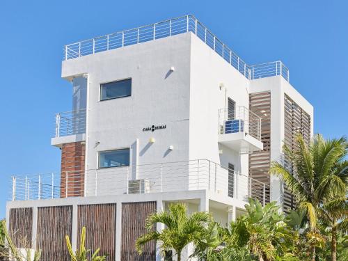 a white building with palm trees in front of it at CASA DUMAI OceanVilla NAKIJIN in Nakijin