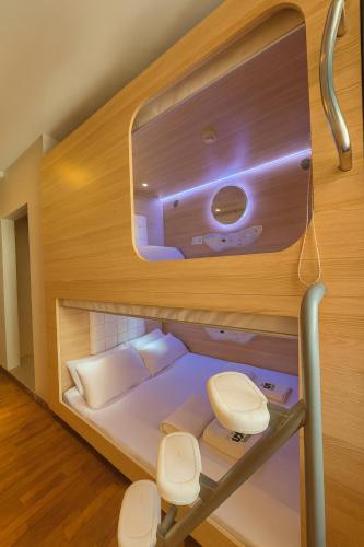 a bunk bed in a room with two white chairs at Wink at Upper Cross Street in Singapore