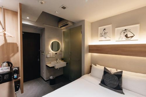 una stanza d'albergo con un letto e un lavandino di Hotel NuVe a Singapore