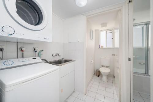 a white kitchen with a sink and a microwave at Windbourne unit 4 Golden Beach QLD in Golden Beach