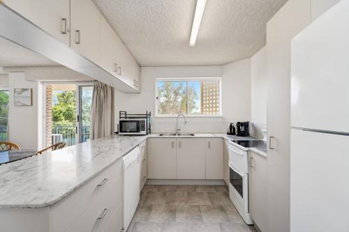 a white kitchen with a sink and a microwave at Windbourne unit 4 Golden Beach QLD in Golden Beach