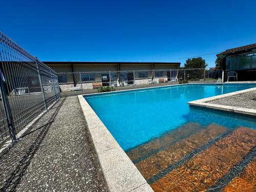 a swimming pool with blue water in a building at Spanish Lady Motel in Napier