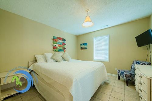 a bedroom with a bed and a chair and a tv at Cg Beach Bungalow #3 in Myrtle Beach