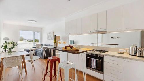 a kitchen with white cabinets and a table with a counter at Stylish Apartment in Melbourne