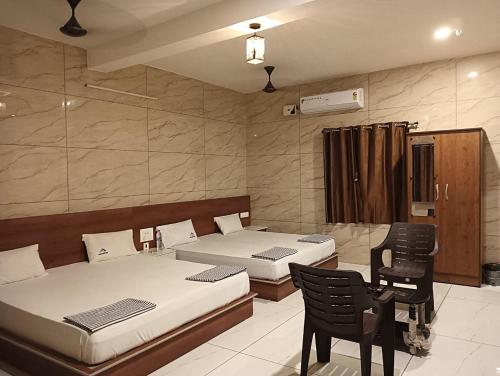 a bedroom with two beds and a table and chairs at Limra Farm House in Pollāchi
