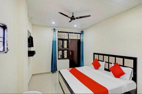 a bedroom with a bed with red pillows and a ceiling fan at Gold Hotel in Faridabad