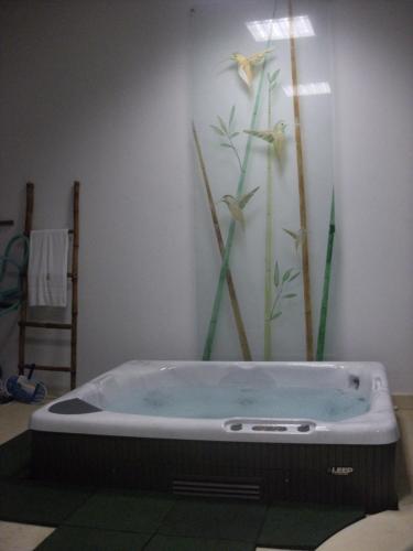 a bath tub with a flower painting on the wall at Cantinho das Buganvilias AT**** in Queimada