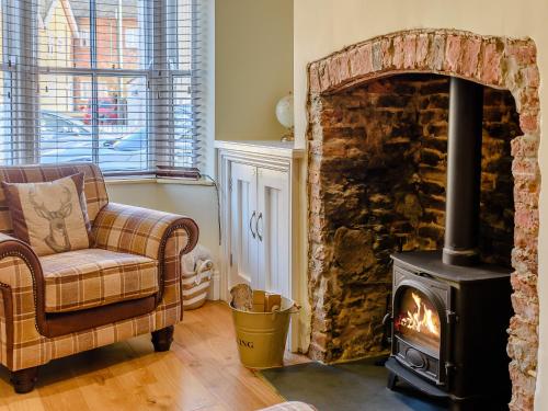 a living room with a fireplace and a chair and a stove at Hidden Winds Cottage in Guisborough