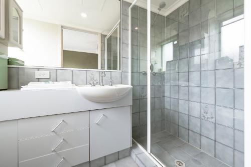 a white bathroom with a sink and a mirror at Surfers Tradewinds in Gold Coast