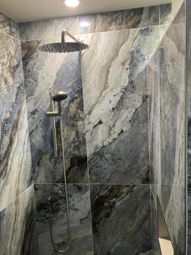 a bathroom with a shower with a stone wall at Luxury oceanfront escape in Neguac