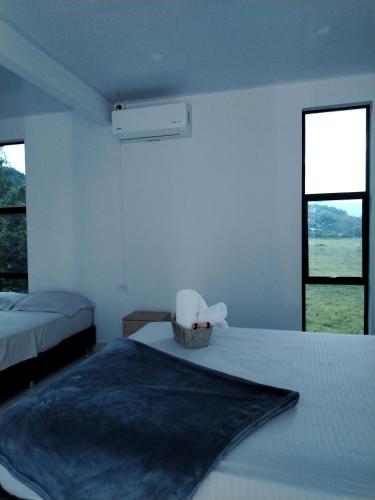 a white room with two beds and two windows at Cabaña Moderna a 1km del Centro de Tauramena in Tauramena