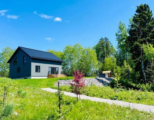 a house in the middle of a field at Batiscan - Waterfront Private Spa & Sauna in Saint Adelphe