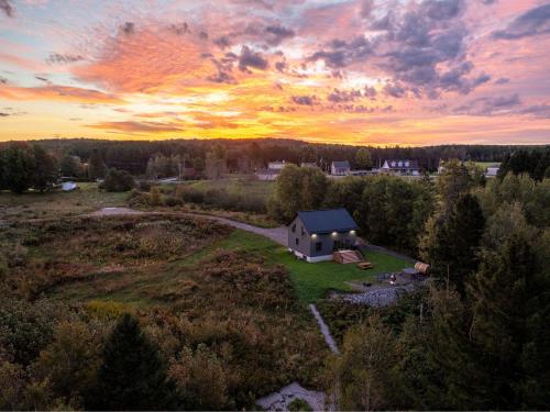an aerial view of a house in a field with a sunset at Batiscan - Waterfront Private Spa & Sauna in Saint Adelphe