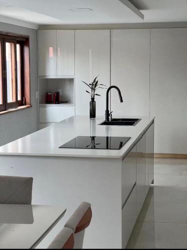 a white kitchen with a sink and a counter at Casa Malta Goiânia in Goiânia
