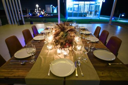 a wooden table with plates and wine glasses on it at Siniya Island Leisure Campground Umm Al Quwain in Umm Al Quwain