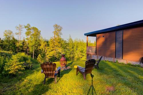 a group of chairs sitting on a lawn next to a cabin at L'Enchanteur - Private Spa & Pet Friendly in Pohénégamook