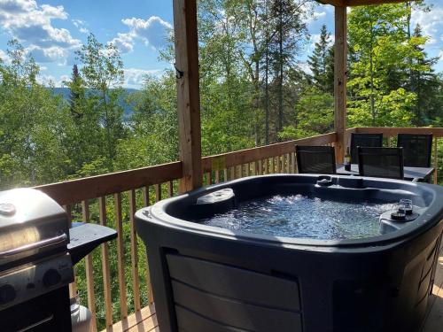 a hot tub on a deck with a grill at L'Enchanteur - Private Spa & Pet Friendly in Pohénégamook