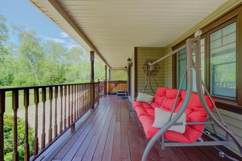 a porch with a red couch on a house at L'Escapade - Spa billard & foyer in Petite-Rivière-Saint-François