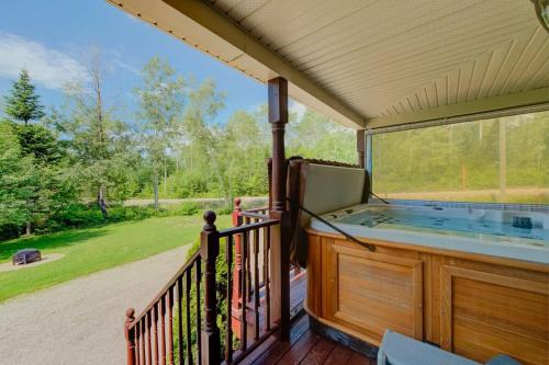 a hot tub on a deck with a large window at L'Escapade - Spa billard & foyer in Petite-Rivière-Saint-François