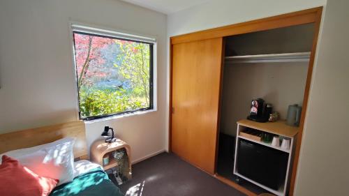 a bedroom with a bed with a window and a tv at Kōwhai Corner Room at Goldfield Heights in Queenstown