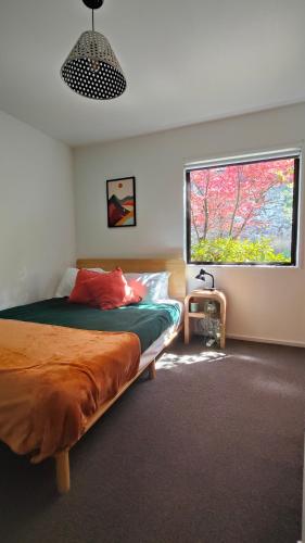 a bedroom with a bed and a large window at Kōwhai Corner Room at Goldfield Heights in Queenstown