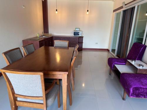 Un comedor con una mesa de madera y sillas moradas. en Prince Hotel Chiang Mai, en Chiang Mai