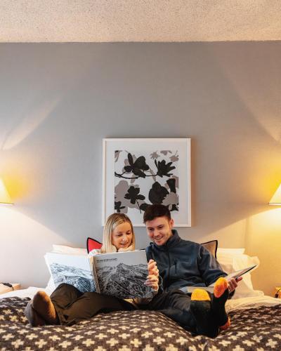 a man and a girl sitting on a bed with a tablet at Chalet Apartments - Mt Buller Apartment Rentals in Mount Buller