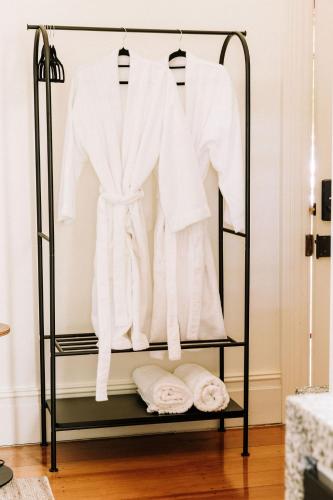 a rack with white coats and towels on it at The Brewers House in Beechworth