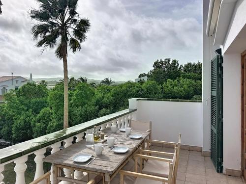 a table and chairs on a balcony with a palm tree at Apartamento con piscina SS19 in Fornells