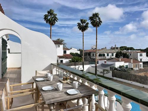 a wooden table on a balcony with palm trees at Apartamento con piscina SS19 in Fornells