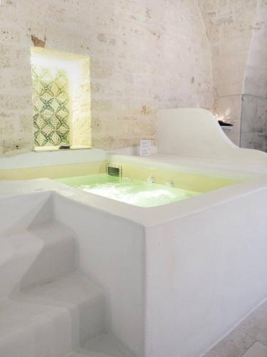 a white bathroom with a sink and a window at Masseria Parco della Grava in Pezze di Greco