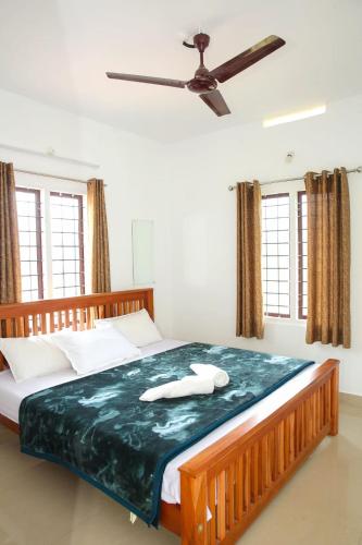 a bedroom with a large bed with a ceiling fan at Blooms home stay in Thekkady