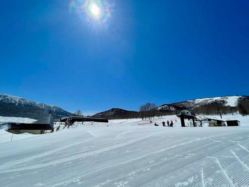 a snow covered field with people standing in the snow at Lodge Yama No Manimani - Nature Stay in Okushiga Kogen in Yamanouchi