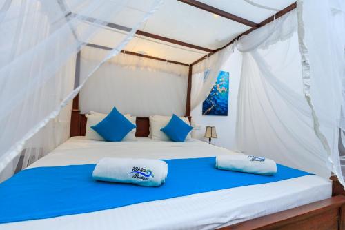 a bedroom with a bed with blue and white pillows at Hikka Boutique in Hikkaduwa