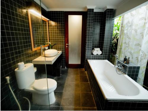 a bathroom with a toilet and a tub and a sink at Pondok Massas Ubud in Ubud