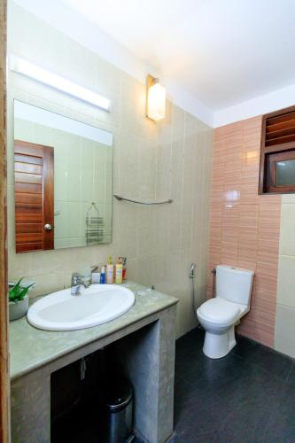a bathroom with a sink and a toilet and a mirror at Hikka Boutique in Hikkaduwa