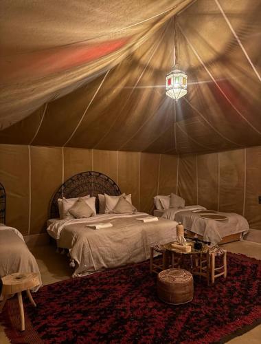 a bedroom with two beds in a tent at Sahara Gift camp in Merzouga