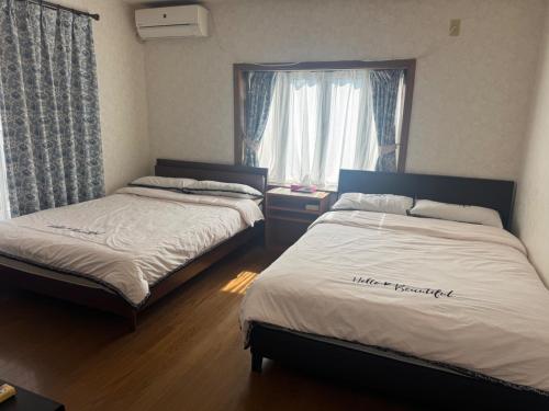 two beds in a room with a window at Family House "2F" - Vacation STAY 12940 in Kumamoto