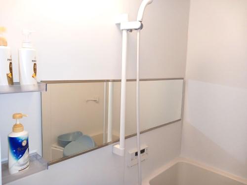 a bathroom with a mirror and a sink at GuestHouseさがら丸 in Niijimamura