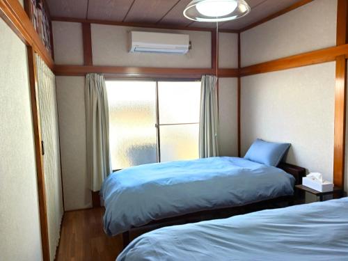 a small room with two beds and a window at GuestHouseさがら丸 in Niijimamura