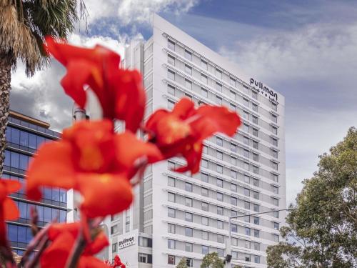 a white building with red flowers in front of it at Pullman Sydney Olympic Park in Sydney