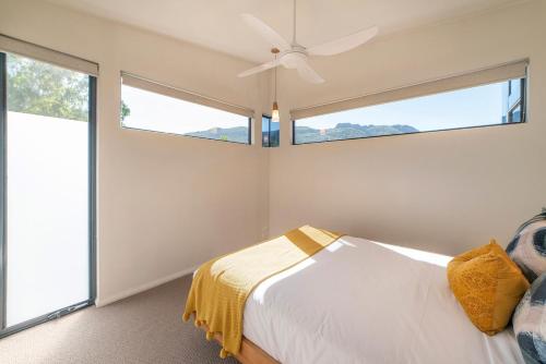 a bedroom with a bed with a ceiling fan and windows at Gumleaf Villa Hosted by Halls Gap Accommodation in Halls Gap